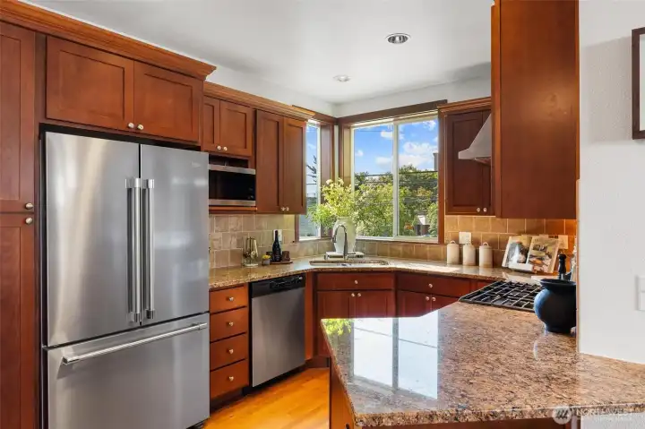 Well-appointed kitchen with rich cabinetry, granite counters, and stainless appliances.
