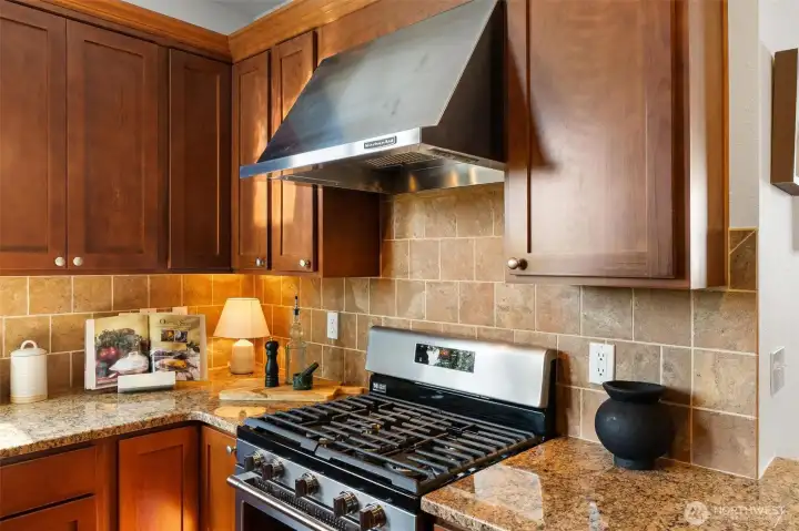 Gas range with vent hood and quality finishes throughout the kitchen.