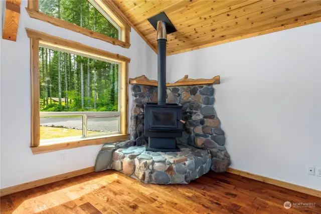 Wood Stove for the chilly days and evenings setting on a River Rock Hearth with Yew Wood Mantel.