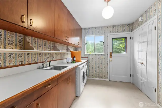 Large laundry with included appliances and sink are nicely situated in mudroom space with door to outside and a powder room