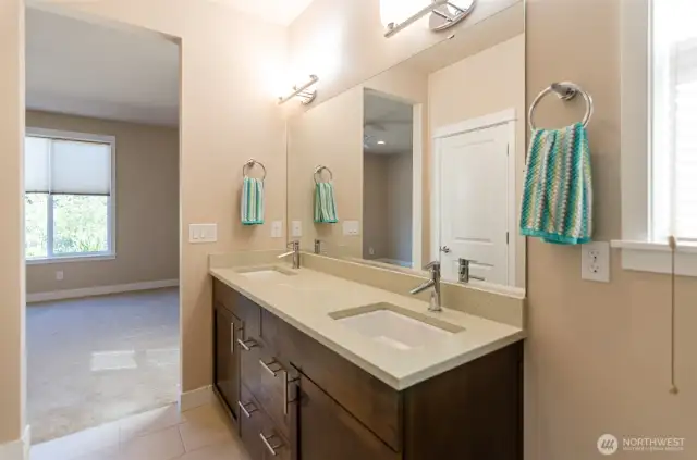 Another view shows double sinks and quartz counter tops.  Private commode.