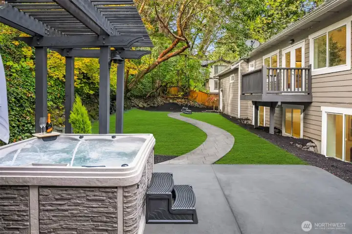Hot tub showing fully fenced backyard and private balcony off main floor primary.