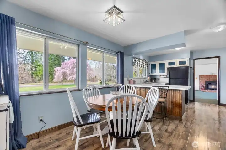Casual dining area framed by a wall of windows overlooking the grounds.