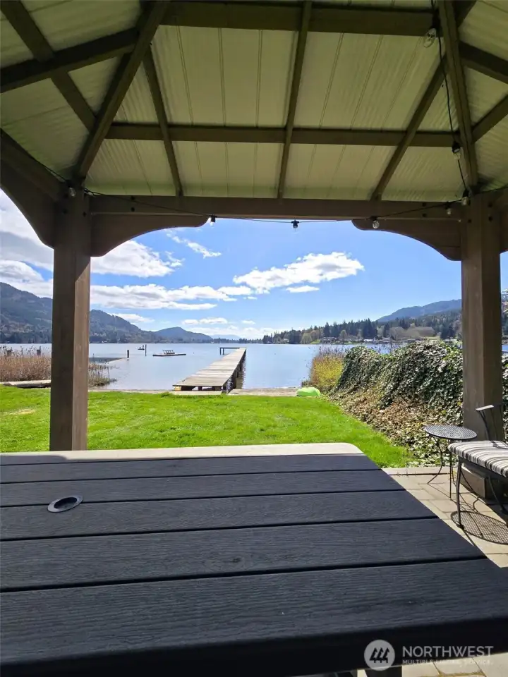 Covered patio with lake view just moments  from Lake Samish, creating a relaxed  outdoor space to enjoy the setting year-round