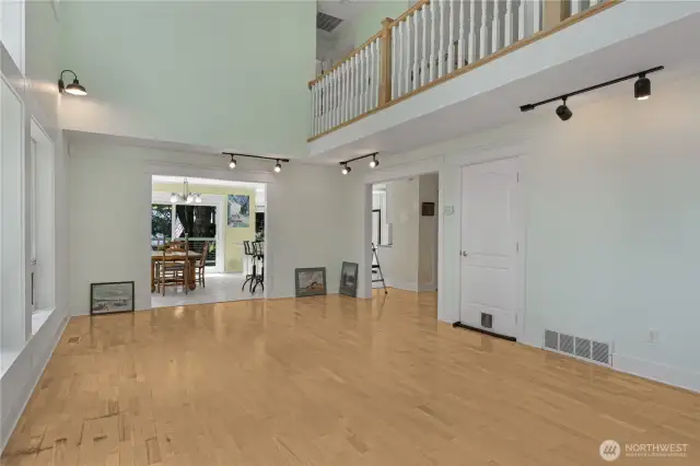 Living room looking into dining/kitchen area plus upstairs balcony.