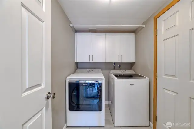 Well appointed laundry room features top-end appliances, a gas dryer, and upper cabinetry for added storage.
