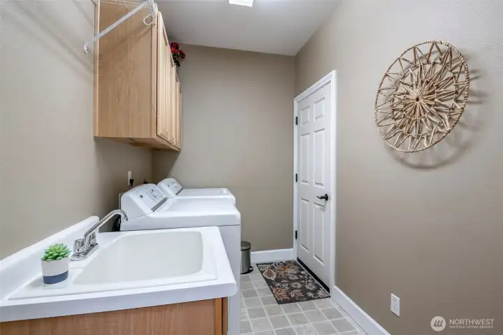 Sizeable laundry room off garage also hosts utility sink and additional storage.