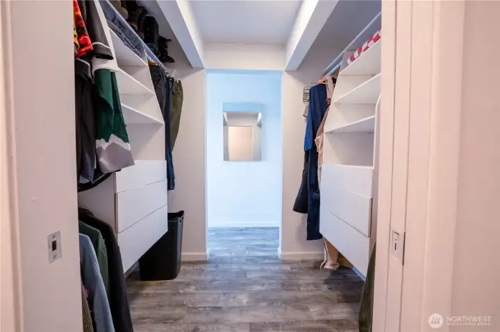 Walk through primary closet connecting bedroom and bathroom