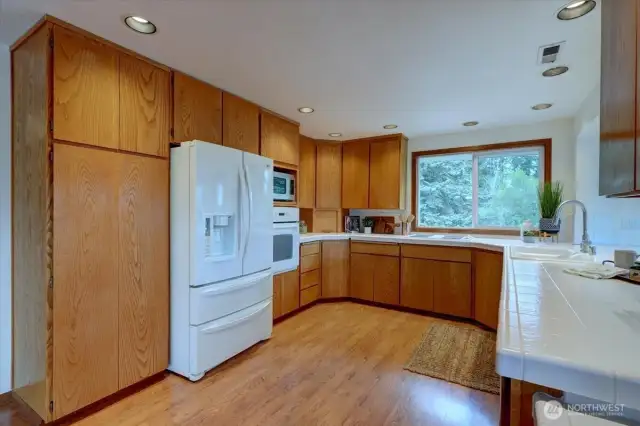 The sprawling kitchen offers lots of wood cabinetry with slide outs & lazy Susan's and tile countertops. The NEW French door fridge with ice & water is included