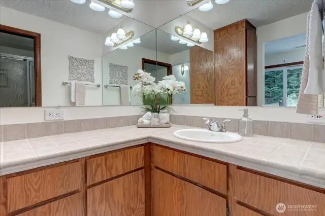 The primary bath offers plenty of wood cabinetry and tile countertops