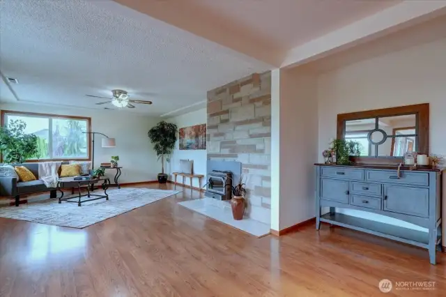 The spacious great room features laminate flooring and a cozy wood stove insert with stone surround
