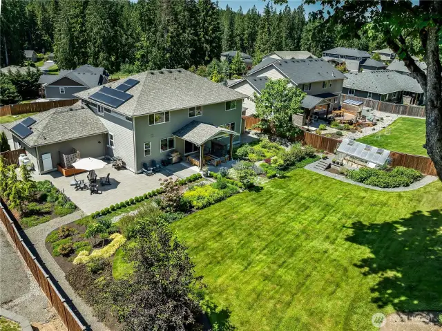 A backyard oasis featuring $180K in outdoor design - covered patio, hardscaping, gas fireplace, greenhouse, solar panels & power wall.