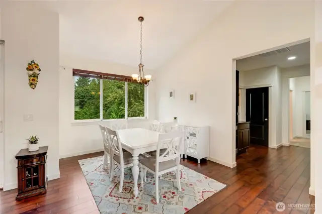 Adjacent to the living room, a formal dining area is highlighted by a stylish chandelier and a large window that fills the space with natural light, making it perfect for entertaining or intimate family meals.