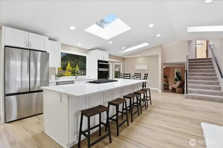 Remodeled kitchen with quartz island, skylights, abundant storage, and seamless connection to dining and living spaces.