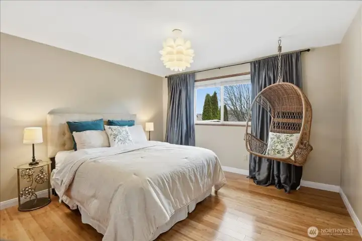 Bright and spacious guest bedroom with hardwood floors and a comfortable, versatile layout.