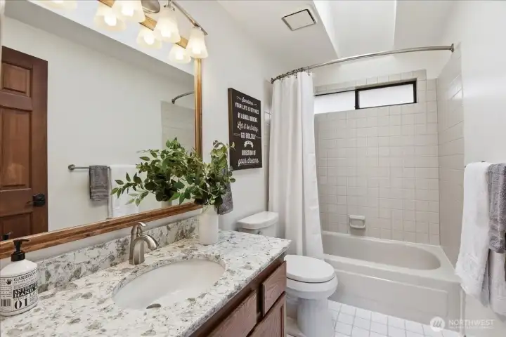 Well-kept guest bath with quartz vanity, tile floors, and a bright, functional layout