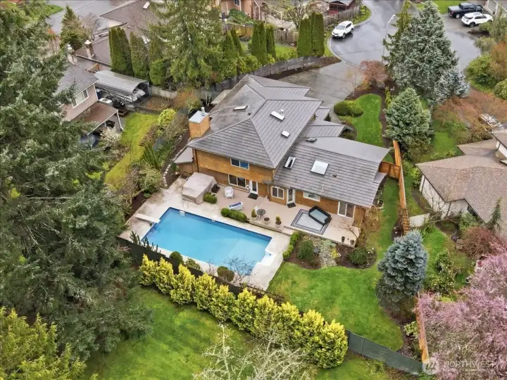 Aerial view highlighting the private backyard oasis with in-ground pool, hot tub, composite deck, and lush landscaping.