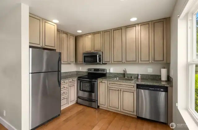 Apartment living space with complete kitchen with stainless steel appliances and washer and dryer