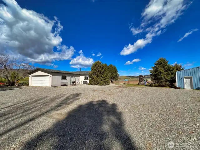 Fully graveled driveway parking area with ample turn around area & RV parking between home and outbuildings
