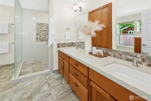 The updated primary bathroom with dual sinks, an oversized shower, built-in wood cabinetry plus heated floors.