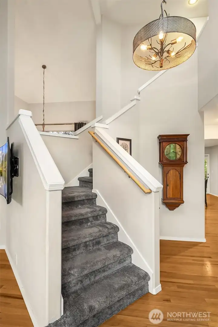 Stairs in the center of the home for the higher sought after circular floorplan. Extra drama with the high ceilings open stair case and custom lighting. And note the TV with no wires! The TV is cleverly wired under the stairs into the coat closet keeping all your devices out of site!
