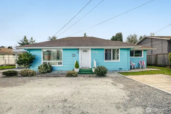 Charming turquoise single-story home in Everett, WA with spacious gravel parking area and inviting curb appeal.