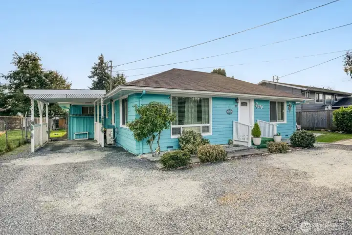 Updated ranch-style exterior with covered carport, large driveway, and fully fenced lot ideal for multiple vehicles.