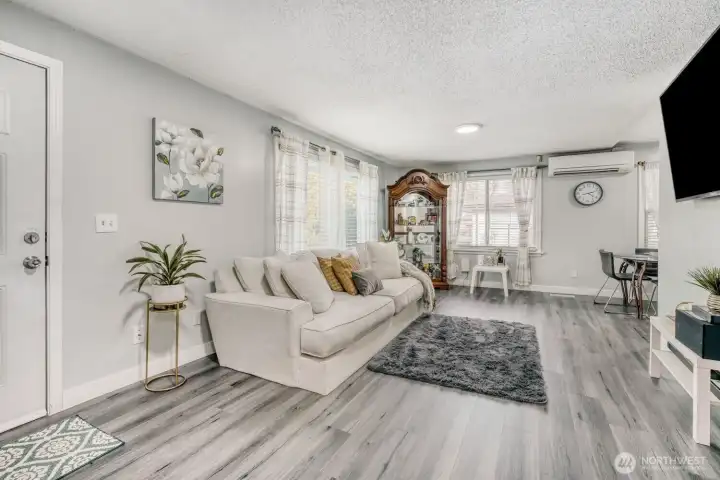 Bright open living room with luxury vinyl plank flooring, recessed lighting, and abundant natural light.
