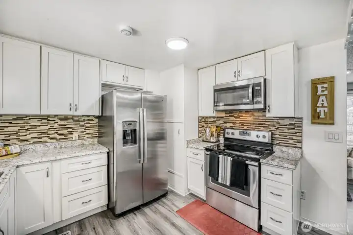 Bright kitchen workspace with double sink, large window, and modern appliance package.