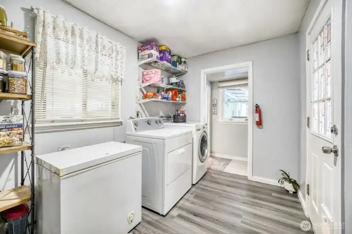 Dedicated laundry space with washer, dryer, and storage shelving.