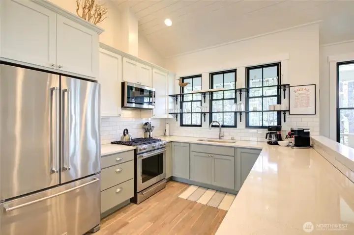 This charming kitchen is so well appointed and very pretty to look at with it's two toned painted cabinets, quartz counters, stainless appliances and window shelving.