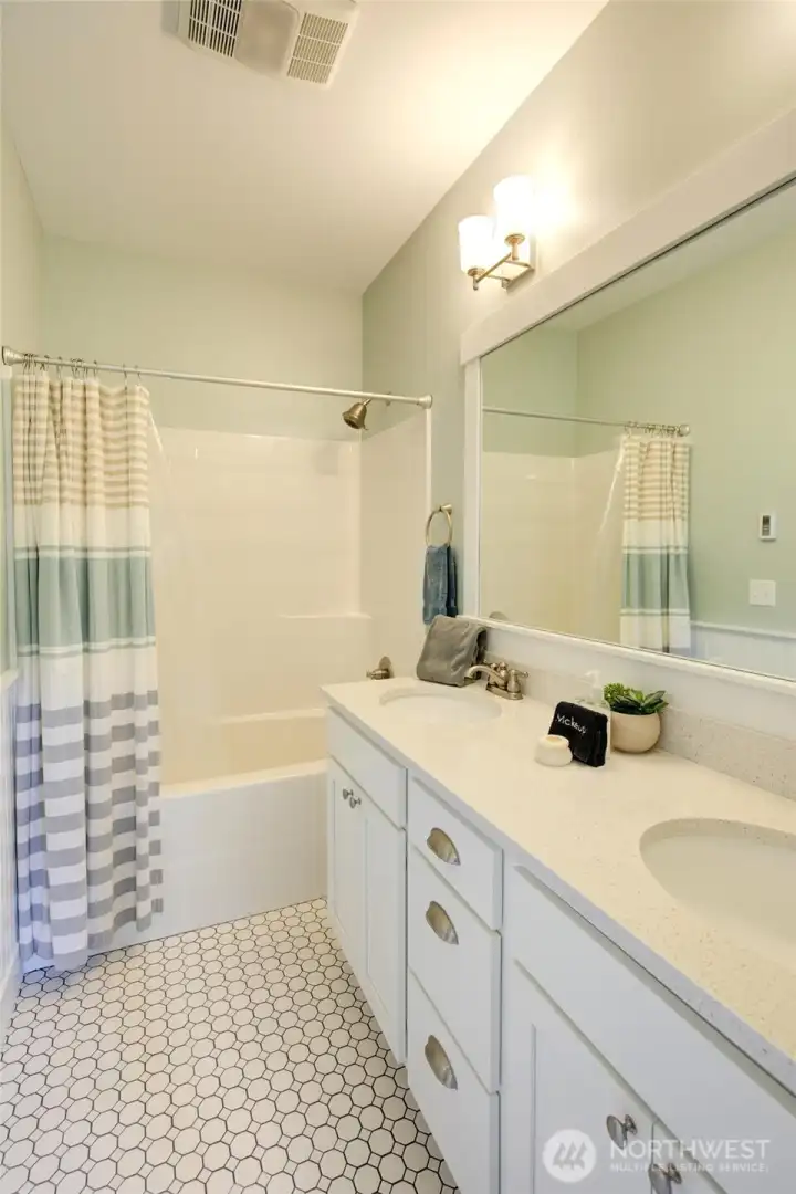 Another bath with a double quartz vanity with lots of storage and tiled floor.