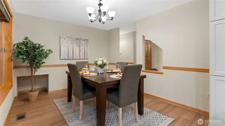 The dining area off the kitchen. There is a little storage nook or a possible space for pet bowls in the corner (behind the tree).