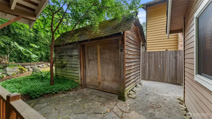 The charming storage shed offers a place to store yard tools to keep them out of the garage.