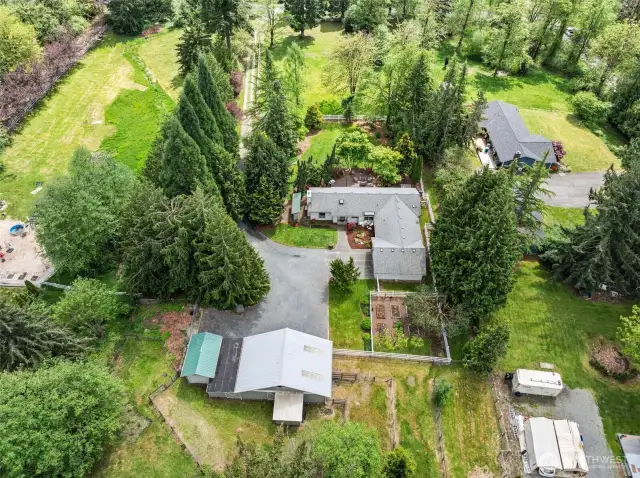 From above, this 2+ acre gem shines with its sprawling landscape, outbuildings, and inviting home.