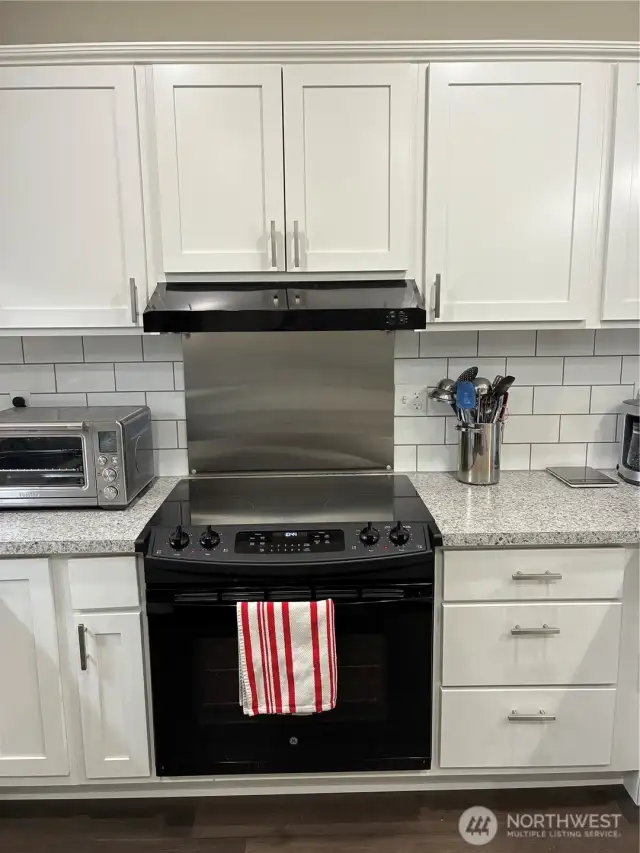 Stove has front operating dials and stainless steel backsplash.