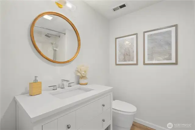 Remodeled hallway guest bathroom with Bedrosian tile surround (tiled to ceiling), soaking depth tub, quartz countertop, LVP flooring and modern fixtures + mirror.