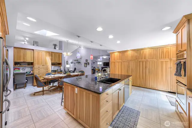 Tile floor, natural granite countertops, custom built solid wood cabinets. Sink on island.