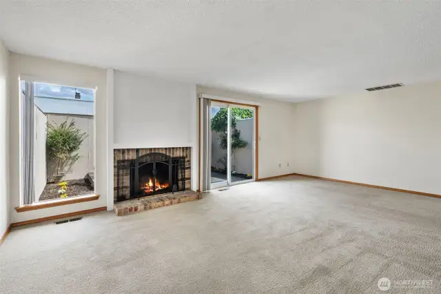 Spacious living room with wood burning fireplace and courtyard access