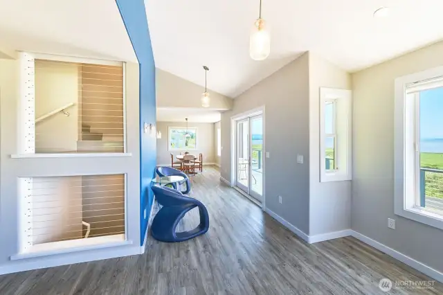 Stairwell cutout draws daylight to the central staircase. South facing hall with French doors to deck, connects living and dining/kitchen areas.