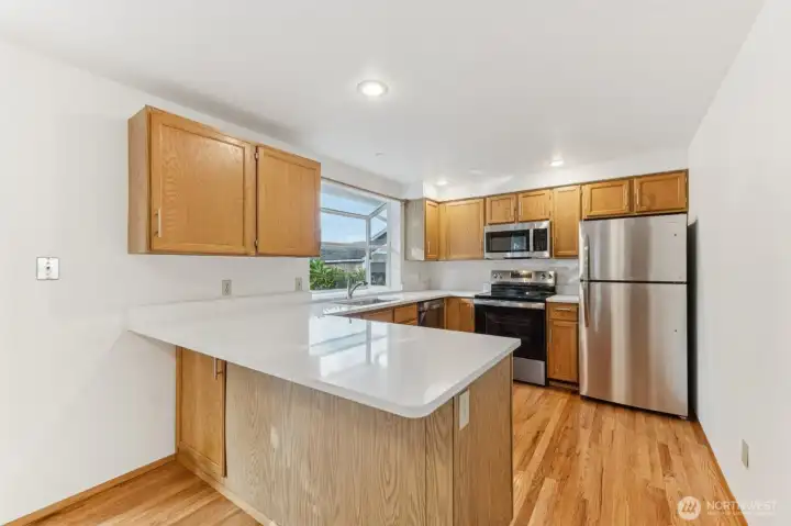 Kitchen with eating bar has all new appliances, sink and quartz countertops.
