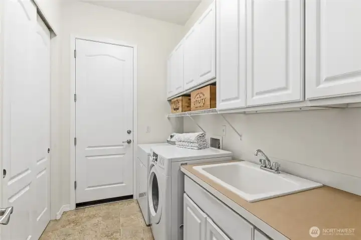Laundry room with a double storage closet, laundry sink and lots of cabinets.
