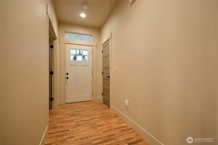 Entry way with distressed laminate wood floors, Coat closet and 4th bedroom/office to the left. 9 ft ceilings throughout the home. Designer paints.