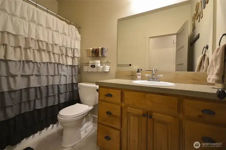 Wonderful full guest bathroom featuring a walk-in shower, alder wood vanity, and tile flooring.