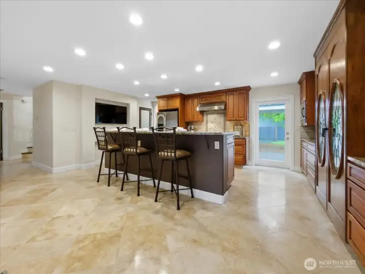 Large kitchen with eating space, custom built-in wine cabinet, and travertine floors.