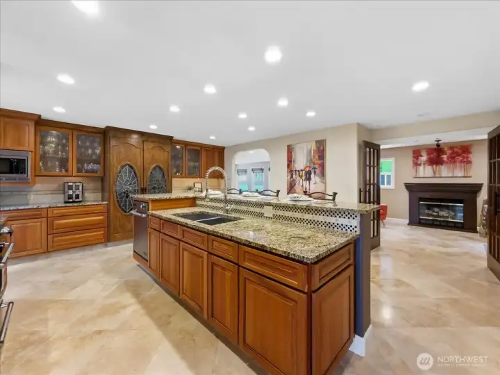 Large kitchen with eating space, custom built-in wine cabinet, and travertine floors.