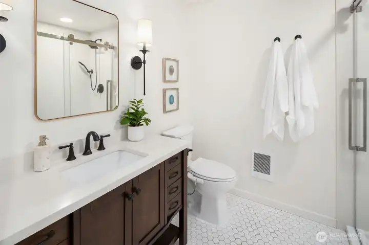 Updated primary bath with newer vanity, tile floors, glass shower Updated primary bath with newer vanity, tile floors, glass shower