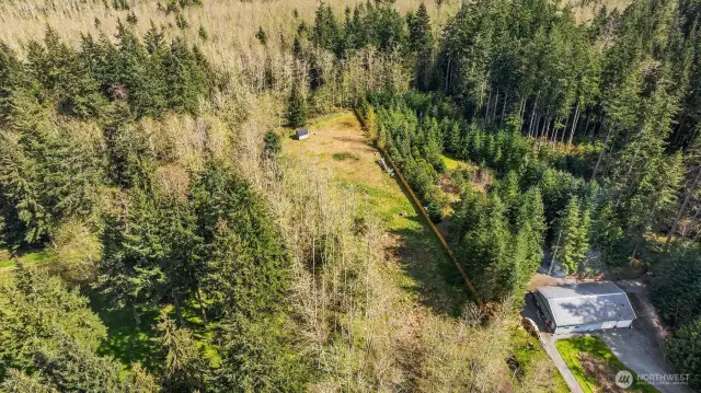 This is a view of the property that shows the cleared building area, the fence line and the neighbor that shares the driveway off the Highway.