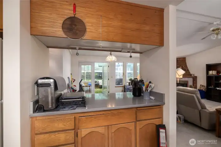 From inside the kitchen, looking out toward the great room.  Dining area immediately ahead and sunroom beyond the French doors
