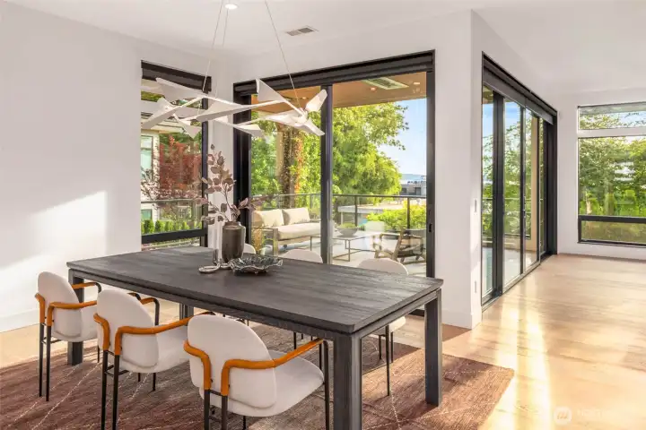 Dedicated dining space framed by designer curated hanging light fixture and flanked by well appointed custom wet bar, wine room, and sliding glass door leading to covered outside entertaining space